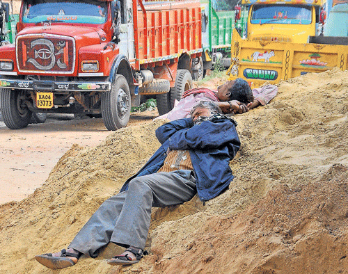 No end in sight: Truck workers rest at a sand depot on  Hebbal Ring Road in Bangalore, following a State-wide strike by sand lorry owners.  dh photo