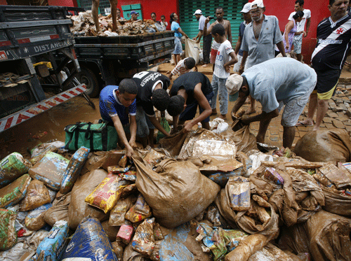 People collect discarded food drenched in mud and rain, outside a supermarket in the Itaguacu municipality, Espirito Santo state, Brazil, Wednesday, Dec. 25, 2013. Civil defense officials say the death toll in the floods and mudslides caused by heavy downpours in two states in southeastern Brazil has risen. More than 50,000 have been forced to leave their homes. AP