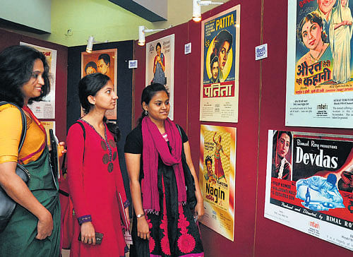 eye-catching: Visitors appreciate posters of Indian movies on display at an exhibition held as part of the Bengaluru International Film Festival in the City on Friday. DH Photo