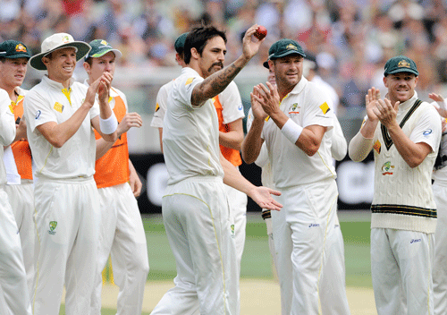 Australia's Mitchell Johnson, center, holds up the ball after taking 5 wickets against England during their Ashes cricket test match, Friday, Dec. 27, 2013, at the Melbourne Cricket Ground in Melbourne, Australia. AP Photo