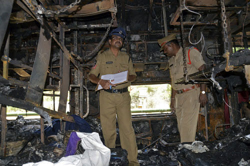 Police officers examine a damaged coach after a fire broke out on a train at Kothacheruvu town in Anantapur district in the southern Indian state of Andhra Pradesh December 28, 2013. At least 23 people were killed on Saturday when the fire broke out, authorities said, the cause of which was not immediately known. The train was on its way from the city of Bangalore to Nanded in Maharashtra. The driver stopped the train when he saw flames coming out of an air-conditioned coach, media reports said. REUTERS