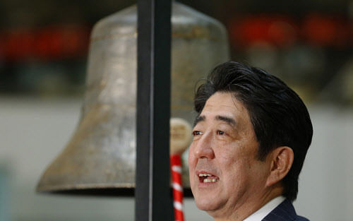 Japanese Prime Minister Shinzo Abe poses for photographers after sounding a bell during a ceremony marking the last session of the year 2013 at the Tokyo Stock Exchange in Tokyo on Monday, Dec. 30, 2013. Reuters.