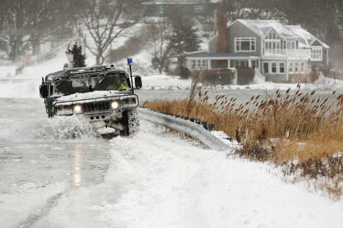 A police vehicle drives through a flooded street during a winter nor'easter snow storm in Scituate, Massachusetts January 3, 2014. A heavy snowstorm and dangerously cold conditions gripped the northeastern United States on Friday, delaying flights, paralyzing road travel and closing schools and government offices across the region. REUTERS