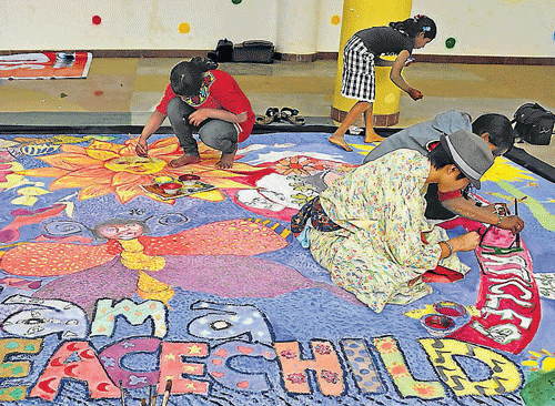 Children busy painting a banner at the Metro Rangoli Art Centre in  the City on Saturday. DH Photo