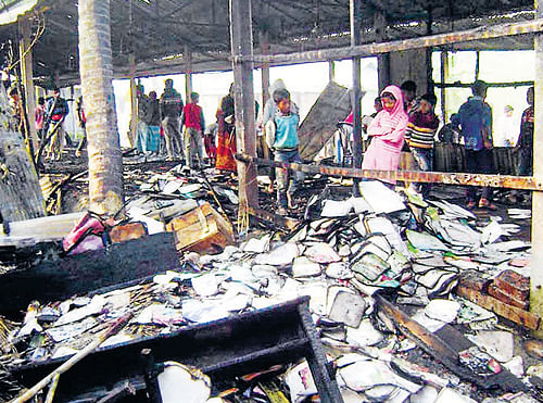 democracy under fire: People look at burnt textbooks after a primary school which was supposed to be used as a polling booth was set on fire on Saturday in Feni in Bangladesh.  REUTERS