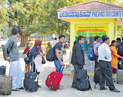 People wait at the pre-paid taxi stand at the City Railway Station. DH Photo