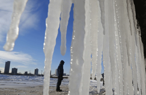 A man is framed by icicles along a beach in Chicago, Illinois, January 7, 2014. A deadly blast of arctic air shattered decades-old temperature records as it enveloped the eastern United States on Tuesday, cancelling thousands of flights, driving energy prices higher and overwhelming shelters for homeless people. REUTERS