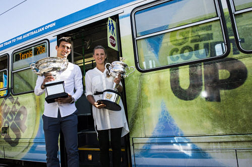 In this photo released by Tennis Australia, defending champions Serbia's Novak Djokovic and Victoria Azarenk of Belarus pose with their trophies beside a Melbourne tram prior to the official draw at the Australian Open tennis championship in Melbourne, Australia, Friday, Jan. 10, 2014. AP Photo