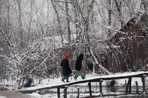 Women walk on a snow covered wooden bridge after fresh snowfall, in the outskirts of Srinagar, India, Thursday, Jan. 9, 2014. Traffic on the 300 kilometers (186 miles) long Jammu-Srinagar national highway has been suspended due to heavy snowfall, according to news reports. AP photo
