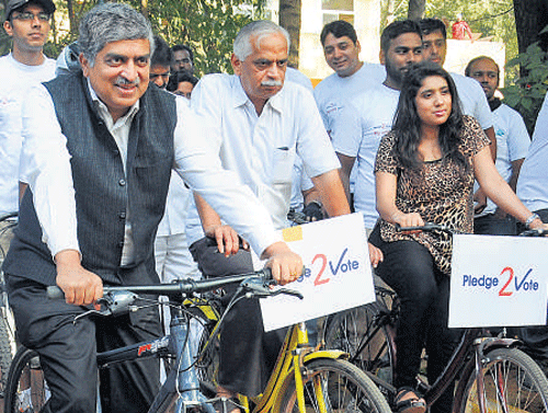 UIDAI chief Nilekani and MLA Vijayakumar take part in a  bicycle rally, to create awareness among voters in the City on Sunday.  dh photo