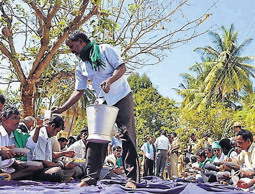 Members of State Sugarcane Growers' Association who staged a day-long protest in front of Revenue Minister V Sreenivas Prasad's residence are seen having lunch, in Mysore, on Monday. DH PHOTO
