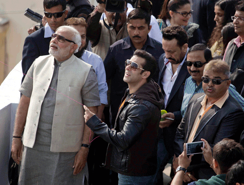 Bollywood actor Salman Khan, center, flies a kite as Gujarat state Chief Minister Narendra Modi, left, and others watch during the kite festival Uttarayan in Ahmadabad, India, Tuesday, Jan. 14, 2014. Khan is in the city to promote his upcoming movie Jai Ho. (AP Photo)