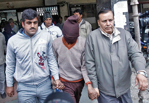 Plain-clothes police escort men (face covered) accused of a gang rape outside a court in New Delhi January 16, 2014. According to the local media, police have arrested two men over the gang rape of a Danish woman. Police said the 51-year-old tourist had filed a police complaint of rape in the district of Paharganj, a popular tourist area packed with backpacker hotels and restaurants near New Delhi railway station. REUTERS