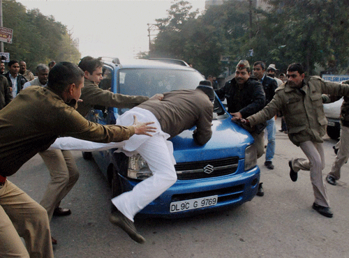 Police personnel trying to stop activist of Hindustan Nirman Dal who jumped in front of Chief Minister Arvind Kejriwal's car during their protest in Ghaziabad on Sunday. PTI Photo