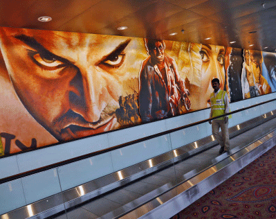 A worker walks near paintings of Bollywood stars displayed on the wall of the new airport terminal at the Chhatrapati Shivaji International Airport in Mumbai. AP photo