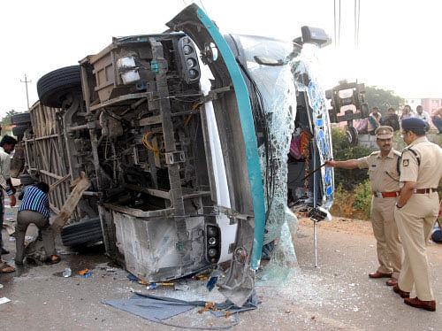 Police officers inspecting the mangled remains of the Volvo bus which met with an accident, belonging to Rajesh travels near Hosakote in the hours on Monday. DH photo