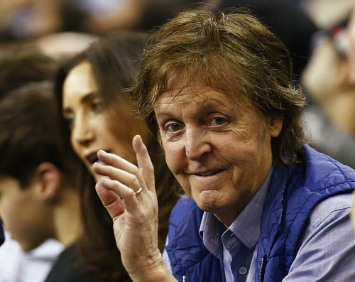 Paul McCartney waves as he watches Brooklyn Nets and the Atlanta Hawks during their NBA basketball game at the O2 in London, January 16, 2014. REUTERS