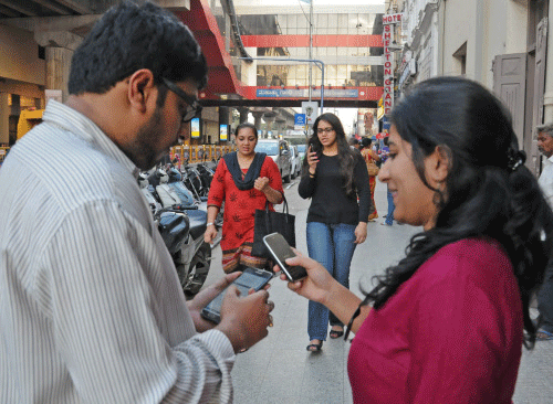 People browsing internet on their mobiles as they connect to free Wi-Fi at MG Road. DH photo