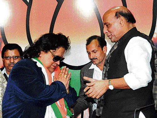Lending his voice: Singer Bappi Lahiri is greeted by BJP President Rajnath Singh after he joined the saffron party in New Delhi on Friday. PTI