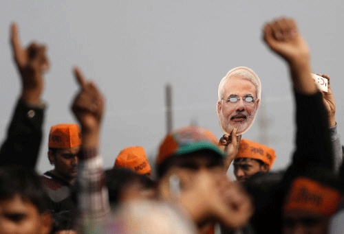 A supporter of Bharatiya Janata Party holds a cut-out of Gujarat's Chief Minister Narendra Modi, prime ministerial candidate for BJP, during a rally ahead of the 2014 general elections, at Meerut. Reuters