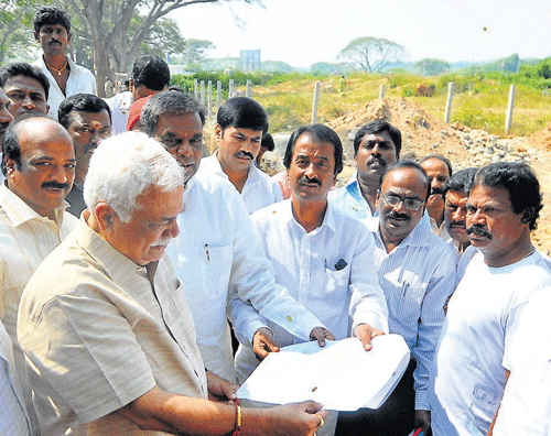 Higher Education Minister R&#8200;V&#8200;Deshpande examines a plan for the proposed women's college at Paduvarahalli, in Mysore, Wednesday. DH Photo