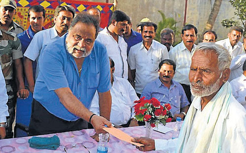 District-in-charge Minister Ambareesh presents a cheque to a cane grower at MySugar factory in Mandya on Friday. MySugar MD Aiyyappa and others are seen.  dh photo