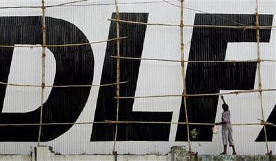 A man paints a logo of Indian property developer DLF Ltd. at their construction site in Mumbai. File photo- Reuters