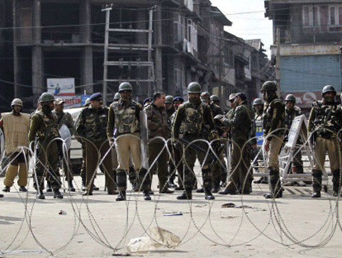 Security personnel stand guard behind concertina wire during strict restrictions in Srinagar February 9, 2014. Authorities imposed restrictions across Srinagar as separatists called for a three-day shutdown to demand for the remains of Mohammad Afzal Guru, a Kashmiri man who was executed on February 9, 2013, for an attack on India's parliament in 2001, local media reported on Sunday. REUTERS