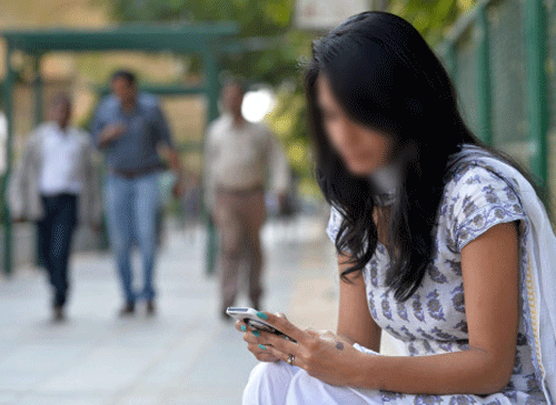 A pedestrian accesses the internet on her mobile phone using the 'Namma Wi-Fi' hotspot on Mahatma Gandhi Road in Bangalore on January 30, 2014. File photo, AFP.