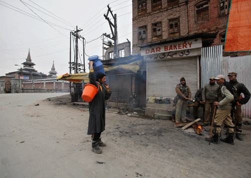 Government forces question a milk supplier as they warm themselves near a fire on a deserted street during a strike in Srinagar. Authorities have imposed restrictions on movement of people in most parts Kashmir after separatists called for a three day strike to mark the execution anniversaries of two separatists in New Delhi. AP