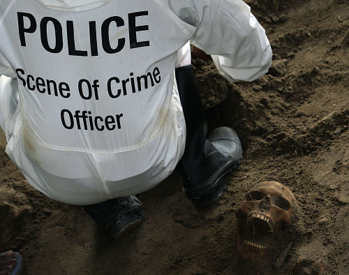 A police officer works next to a human skull at a construction site in the former war zone in Mannar, about 327 km (203 miles) from the capital Colombo, January 16, 2014. The discovery of a mass grave containing more than 30 skulls in northern Sri Lanka has fuelled speculation that there may be many more like it containing the remains of thousands who went missing during the island nation's nearly three-decade war. Reuters.