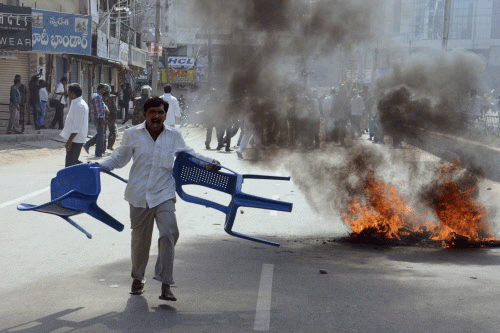 File photo of a supporter of United Andhra Pradesh shouts as he carries chairs to throw at police during a protest in Anantapur district of Andhra Pradesh over the creation of Telangana.  AP photo