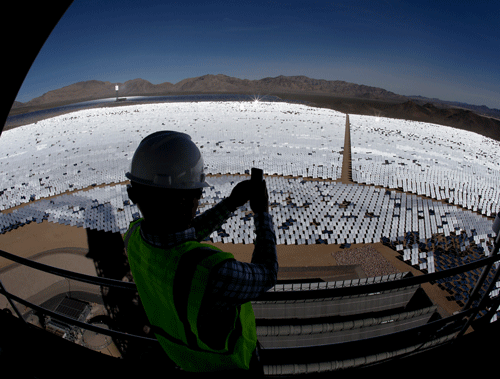 Jeff Holland takes a picture of some of the 300,000 computer-controlled mirrors that reflect sunlight to boilers that sit on 459-foot towers Tuesday, Feb. 11, 2014 in Primm, Nev. The Ivanpah Solar Electric Generating System, sprawling across roughly 5 square miles of federal land near the California-Nevada border, will be opened formally Thursday after years of regulatory and legal tangles. (AP Photo)