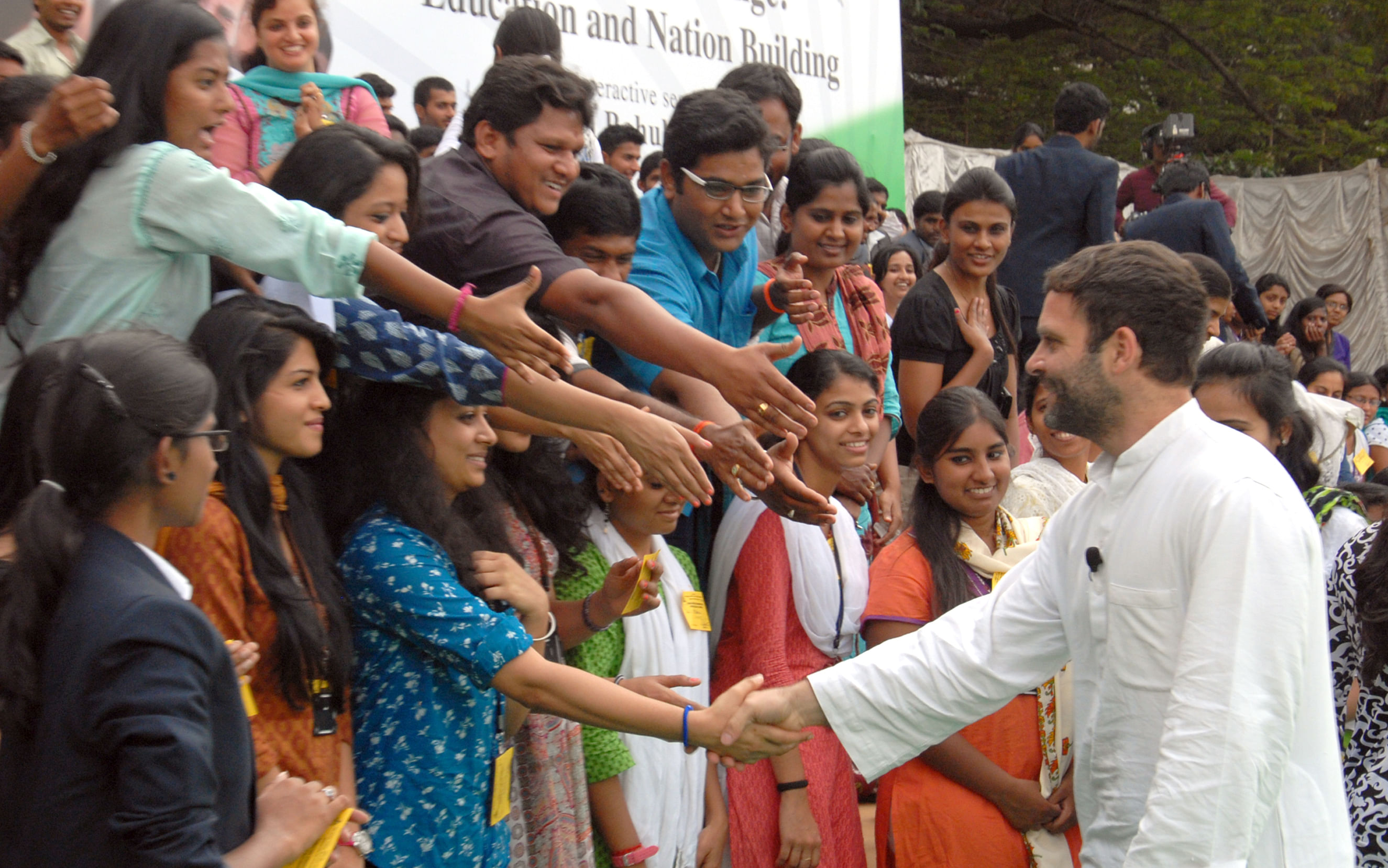 All smiles: AICC vice-president Rahul Gandhi shakes hand with a student at a programme in Central College Grounds in Bangalore on Saturday. DH Photo