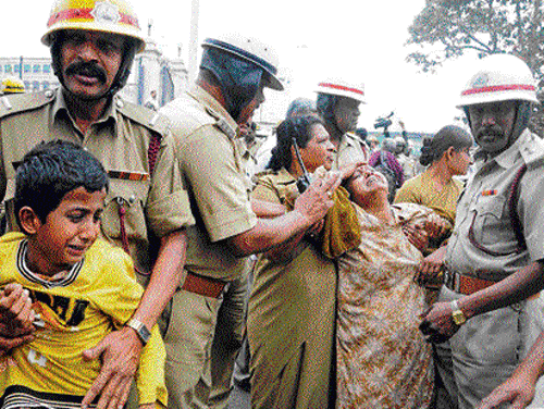 aggrieved: Policemen rein in members of a family from Tumkur district, who threatened to commit suicide in front of the Vikasa Soudha in Bangalore on Friday. kPn