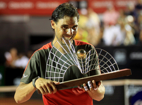 Rafael Nadal of Spain bites his trophy after winning against Alexandr Dolgopolov of Ukraine at the 2014 Rio Open men's final tennis match in Rio de Janeiro, February 23, 2014. REUTERS