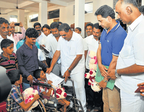District-in-Charge Minister B Ramanath Rai hands over eligibility certificate for availing government pension, to an Endosulfan victim, at a programme at Lions Club hall in Manchi in Bantwal taluk on Thursday. dh photo