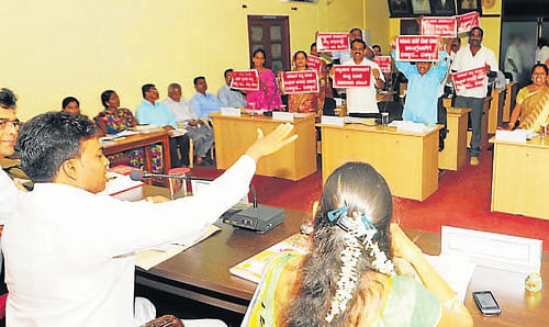 BJP members display red coloured placards against the Congress government, during the CMC&#8200;meeting in Udupi on Friday.