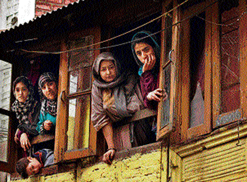 Kashmiri women watch from their home a protest rally by JKLF&#8200;activists in Srinagar on Friday. AP