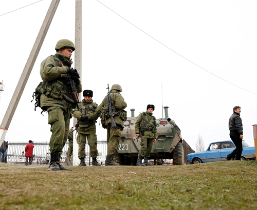 Military personnel stand next to an armoured personnel carrier (APC) in the Crimean port city of Feodosiya March 2, 2014. Ukraine mobilised on Sunday for war and called up its reserves, after Russian President Vladimir Putin threatened to invade in the biggest confrontation between Moscow and the West since the Cold War. REUTERS