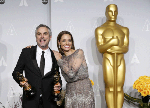 Alfonso Cuaron poses with the awards for best director and best film editing for the film 'Gravity' with presenter Angelina Jolie at the 86th Academy Awards in Hollywood, California March 2, 2014. REUTERS