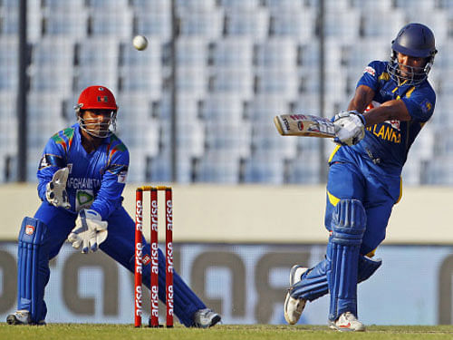 Sri Lanka's Kumar Sangakkara, right, plays a shot as Afghanistan's Mohammad Shahzad watches during their Asia Cup one-day international cricket tournament in Dhaka, Bangladesh, Monday, March 3, 2014. (AP Photo)