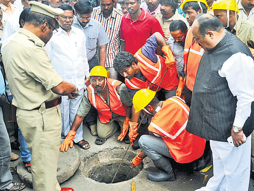 M Shivanna, chairperson of National Commission for Safai Karamcharis, looks at the manhole in Mysore on Monday, where a man was killed while manually clearing it. DH Photo