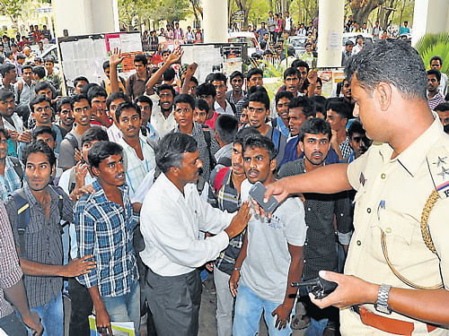 Police personnel try to pacify students protesting in front of Yuvaraja's College, in Mysore, on Monday. DH Photo