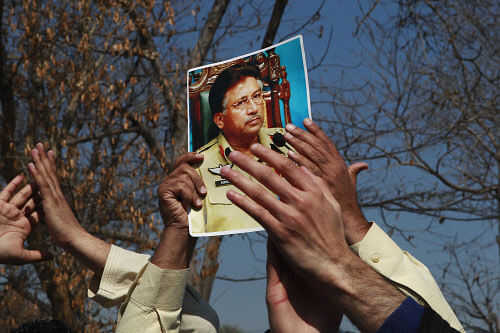 A supporter holds a picture of Musharraf, during a protest at the arrival of him at the Special Courtr in Islamabad