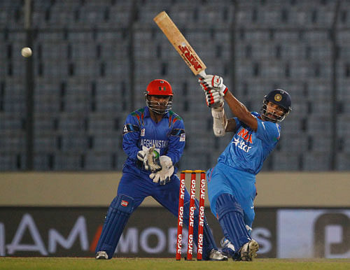 Shikhar Dhawan, right, plays a shot as Afghanistan's Mohammad Shahzad watches during their Asia Cup one-day international cricket match in Dhaka, Bangladesh, Wednesday March 5, 2014. AP