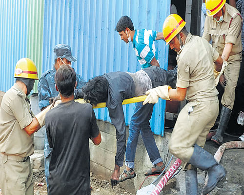 Police and fire personnel carry the body of a worker who was asphyxiated at the Sampath Refinery Private Limited in Mandya on Thursday. DH Photo