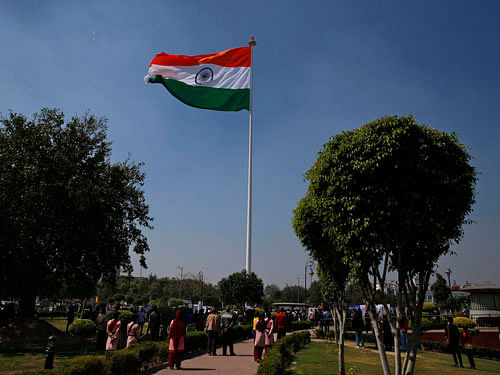 People look at the largest Indian national flag in the country after it is unfurled in New Delhi, India, Friday, March 7, 2014. The flag which measures 90 feet in length, 60 feet in width and weighing 35 kilograms (77 pounds) and supported on a 207 feet flagpole. (AP Photo)