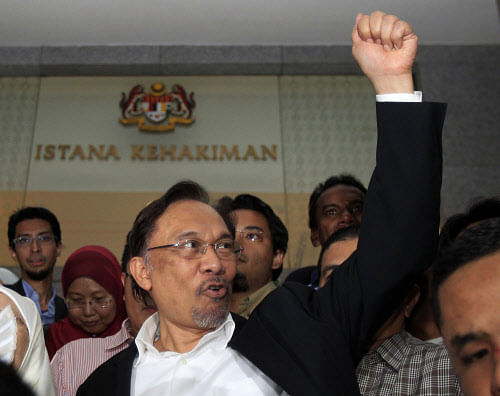 Malaysian opposition leader Anwar Ibrahim gestures as he leaves a courthouse in Putrajaya, Malaysia, Friday, March 7, 2014. A Malaysian court Friday found Anwar guilty on sodomy charges, overturning an earlier acquittal and dealing a major blow to his hopes of contesting a local election this month. (AP Photo/Lai Seng Sin)