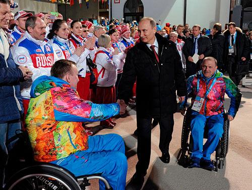 In this photo taken Thursday, March 6, 2014, Russian President Vladimir Putin, center, greets athletes during his visit to the mountain Paralympic village in Krasnaya Polyana, Russia, on the eve of the opening ceremony of the 2014 Winter Paralympics in Sochi. At right is Sergei Shilov, six time Paralympic Champion. AP